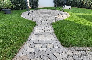 Gereinigter Pflasterweg im Garten. Steinweg zu rundem Platz mit Pavillon. Pflasterreinigung für schöne Außenanlagen. Leistungen im Überblick.