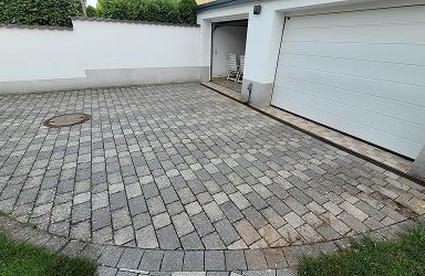 Gereinigte Pflasterfläche einer Einfahrt. Steinreinigung im Außenbereich als Leistung. Vorher Nachher Effekt der Reinigung von Steinen.