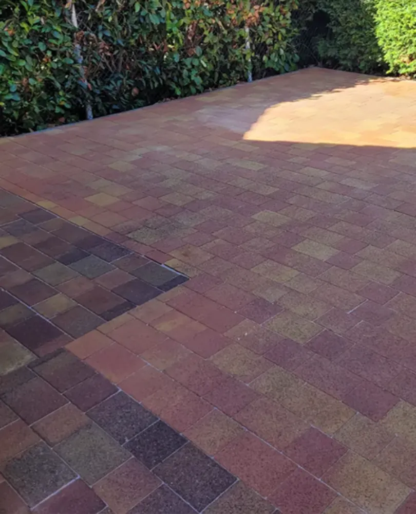 Terrassenreinigung: Vorher-Nachher-Vergleich einer Pflasterfläche. Teilweise gereinigt, deutlicher Unterschied sichtbar.